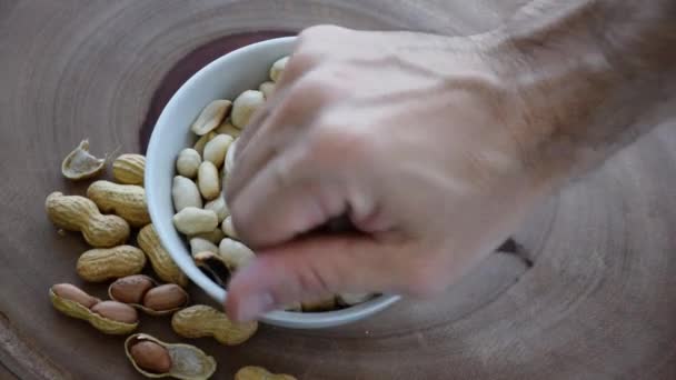 La gente recogiendo cacahuetes de una pequeña porción en el centro. Fondo de madera. - Metraje, vídeo
