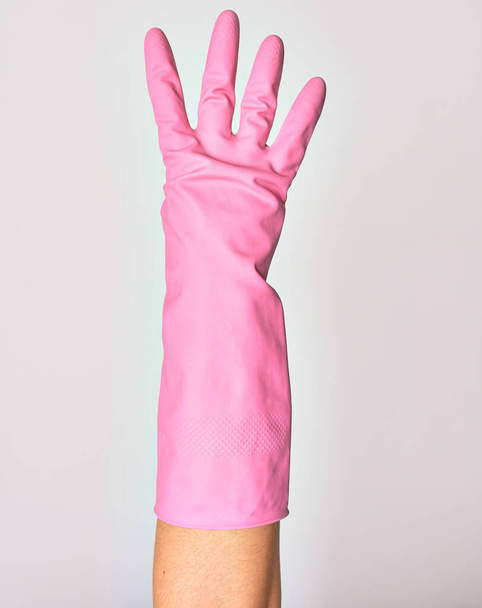 Hand of caucasian young woman wearing pink cleaning glove. Showing fingers doing number four over isolated white background - 写真・画像