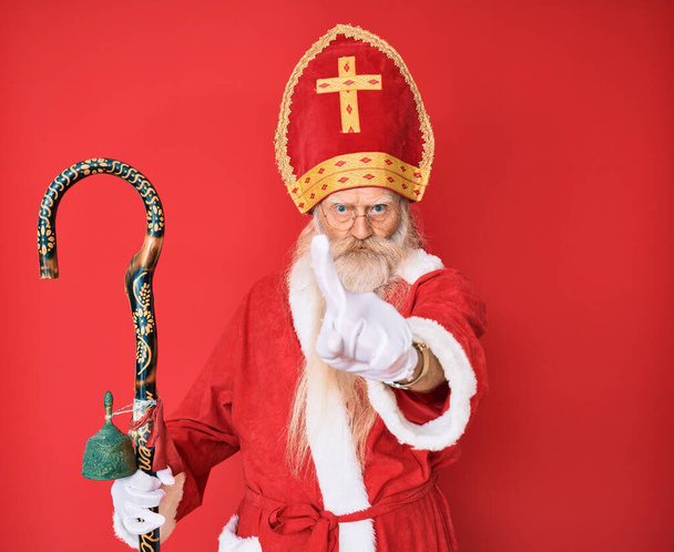 Starý starší muž s šedivými vlasy a dlouhými vousy v tradičním kostýmu svatého Mikuláše, ukazující prstem nahoru a rozzlobeným výrazem, neprojevuje žádné gesto  - Fotografie, Obrázek
