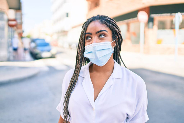 夏の晴れた日に屋外でcovid-19安全マスクを身に着けている若いアフリカ系アメリカ人女性 - 写真・画像