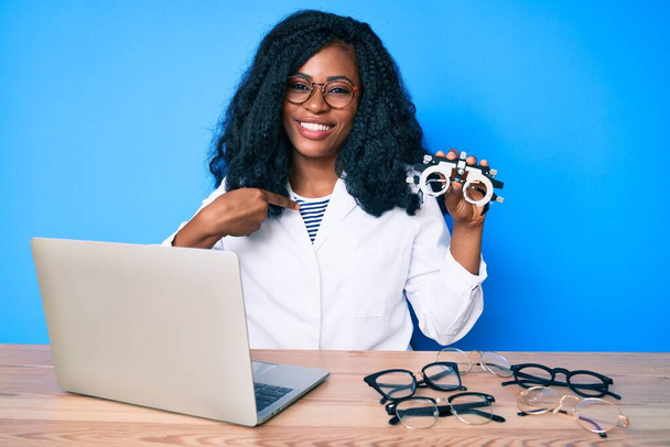 Красива африканська жінка тримає окуляри оптометрії, вказуючи пальцем на одного себе посміхаючись щасливим і гордим
  - Фото, зображення