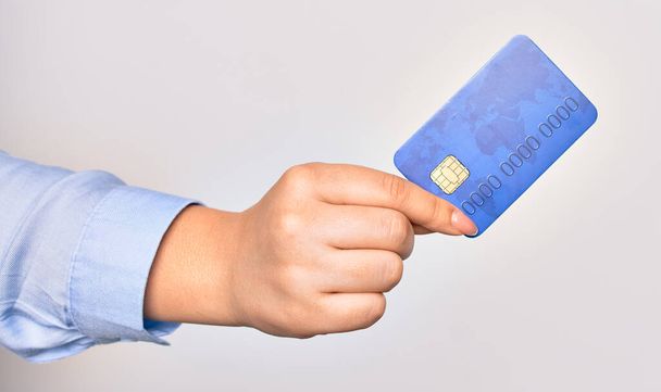 Mano de mujer joven caucásica sosteniendo tarjeta de crédito sobre fondo blanco aislado - Foto, imagen