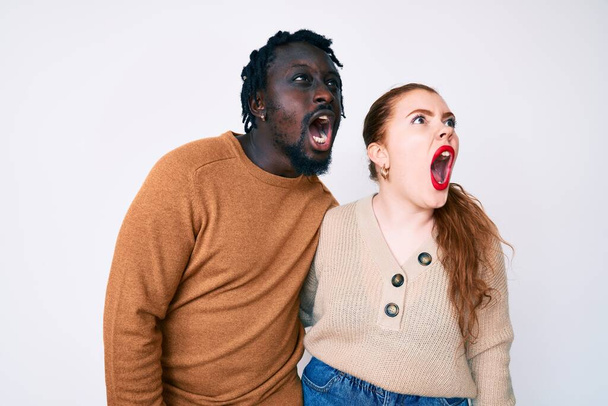 Interracial Paar in lässiger Kleidung wütend und wütend schreien frustriert und wütend, schreit vor Wut. Wut und aggressives Konzept.  - Foto, Bild