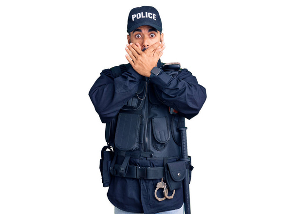 警察の制服を着た若いヒスパニック系の男がミスのために手で口をカバーショックを受けた。秘密の概念.  - 写真・画像