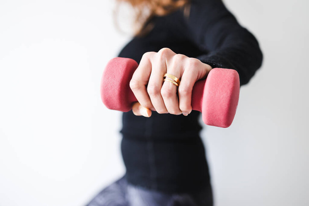 home fitness and online coaching concept, woman in sporty clothes holding dumbbell and exercising the upper body - Foto, Imagen