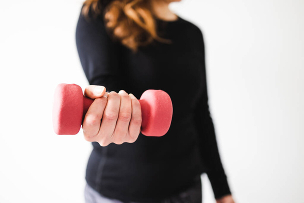 home fitness and online coaching concept, woman in sporty clothes holding dumbbell and exercising the upper body - Foto, imagen