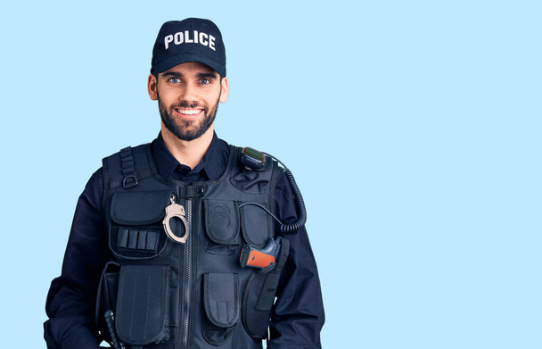 Junger gutaussehender Mann mit Bart in Polizeiuniform mit einem fröhlichen und kühlen Lächeln im Gesicht. Glück gehabt.  - Foto, Bild