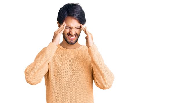 Hombre hispano guapo usando suéter casual con la mano en la cabeza para el dolor en la cabeza porque el estrés. padecer migraña.  - Foto, imagen