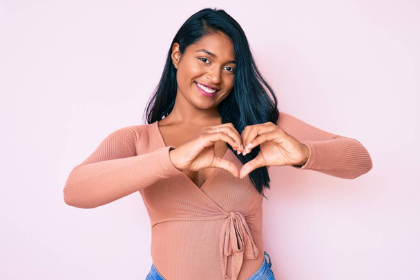 Beautiful latin young woman with long hair wearing casual clothes smiling in love showing heart symbol and shape with hands. romantic concept.  - Photo, Image