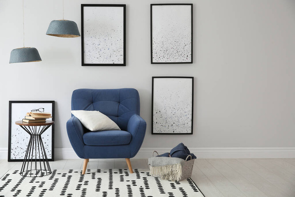 Beautiful artworks and comfortable armchair in stylish room. Interior design - Photo, Image
