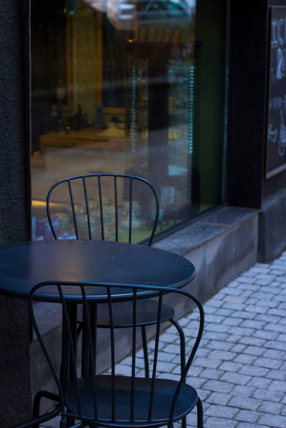 Чорні стільці і стіл на вулиці біля вікна магазину кафе
 - Фото, зображення