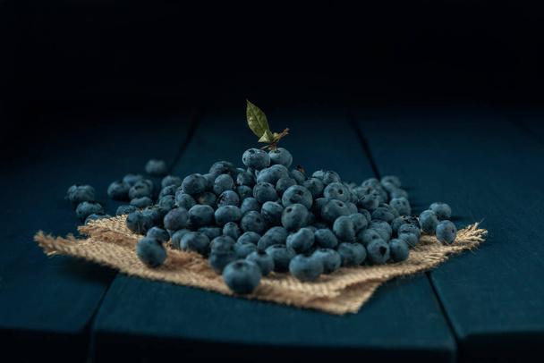 Heap of ripe blueberry with on burlap napkin and the dark wooden table.  - Foto, Bild