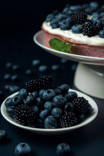 Plate with blackberry and blueberry, cottage cheese casserole on the dark textured background.  - Photo, Image
