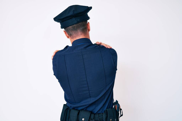 Jeune homme caucasien portant l'uniforme de police s'embrassant heureux et positif à partir de l'arrière. amour de soi et soins de soi  - Photo, image