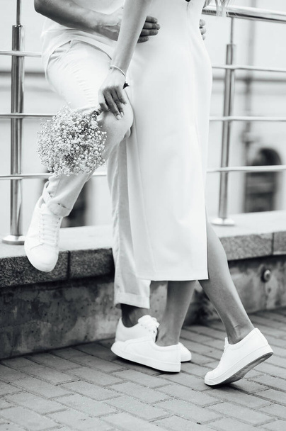A loving couple in white clothes and sneakers hugs with their hands - Foto, Imagen