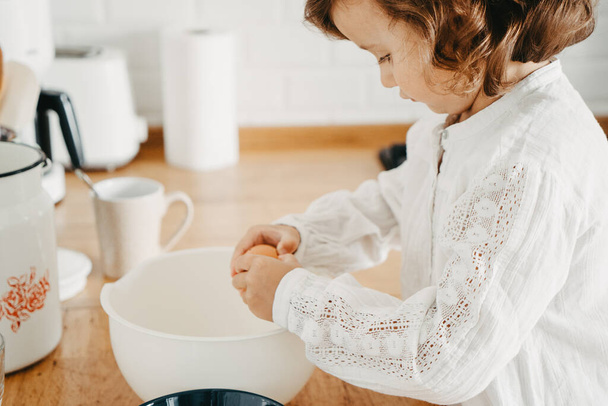 Little girl preparing dough for pancakes at the kitchen. Concept of food preparation, selective focus, close up on details. Casual lifestyle photo series in real life interior - Foto, immagini