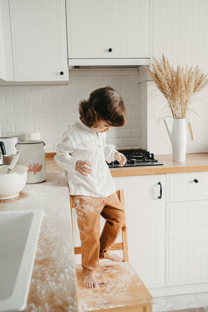 Little girl preparing dough for pancakes at the kitchen. Concept of food preparation, having fun with flour. Casual lifestyle photo series in real life interior - Foto, Bild