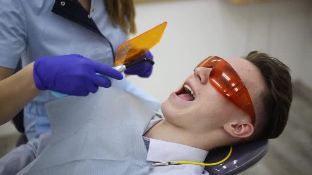 Femme dentiste traitant un jeune homme patient. Protocole chirurgical des implants dentaires avec des outils en clinique dentaire. - Séquence, vidéo