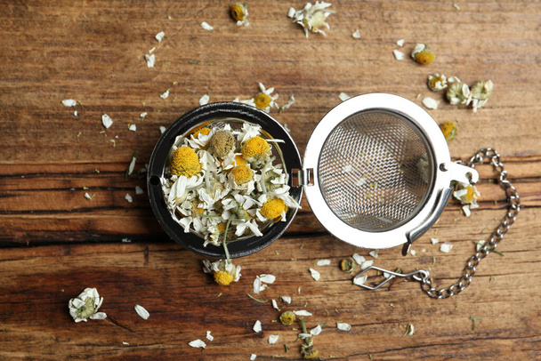 Dry chamomile flowers in infuser on wooden table, flat lay - Photo, Image