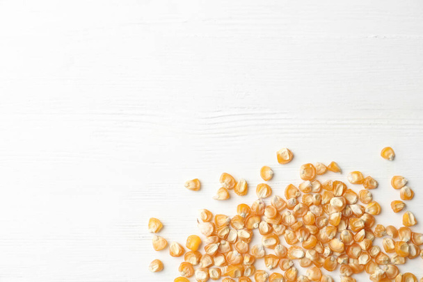 Raw dry corn seeds and space for text on white wooden background, flat lay. Vegetable planting - Foto, Bild