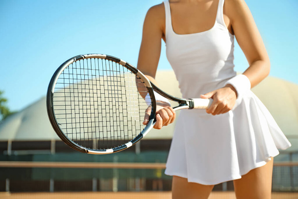 Sportswoman playing tennis at court on sunny day, closeup - Фото, зображення