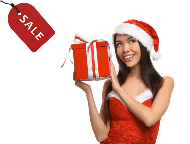 Boxing day. Beautiful Asian woman in Santa costume with Christmas gift and sale tag on white background - Φωτογραφία, εικόνα