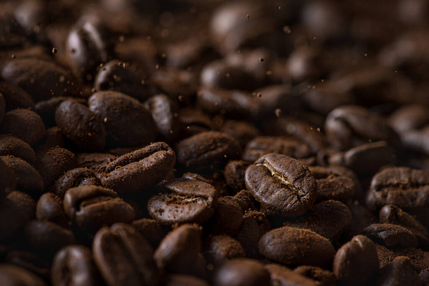 Closeup of falling coffee beans with focus on one in beautiful light - Photo, image