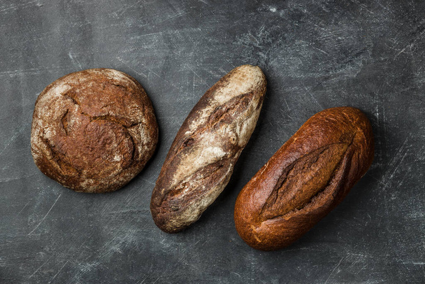 Rustic bread on dark background. Flat lay. - Photo, Image