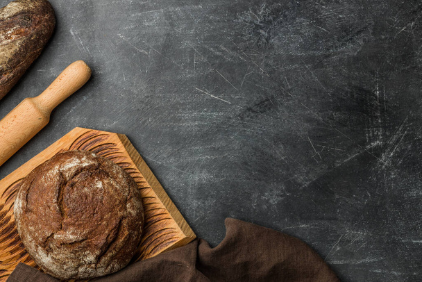Rustic bread of whole wheat grains on dark background with copy space. Flat lay. - Foto, Imagem
