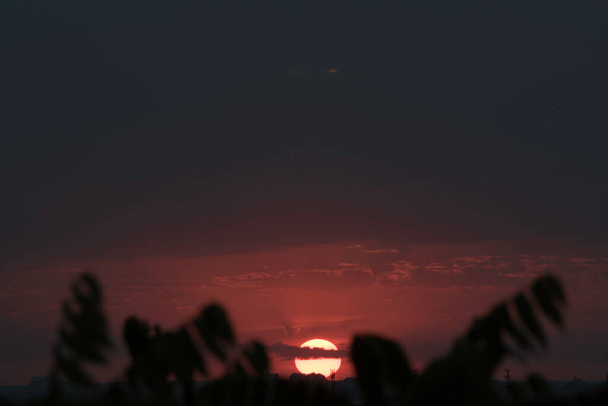 A bíbor ég egy kontrasztos naplemente felett egy nagy város Ukrajnában, a város Harkiv az utolsó másodpercekben, és a nap eltűnik a horizont mögött, lenyűgöző kilátás nyílik a múló nap és a találkozó az éjszaka a nappal. Felhők a horizonton - Fotó, kép