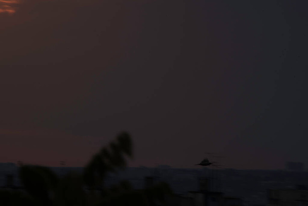 Червоне небо за контрастним заходом сонця над великим містом України, за останні секунди місто Харків і сонце зникнуть за горизонтом, приголомшливий погляд на день і зустріч ночі з днем. Хмари на горизонті - Фото, зображення
