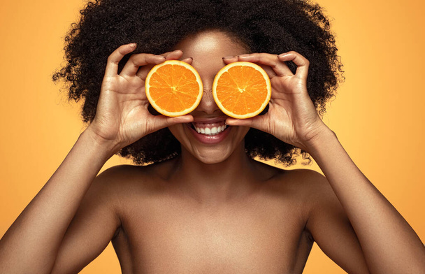 Happy black lady playing with orange - Foto, afbeelding