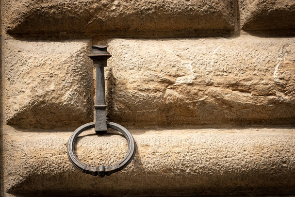 Anel de ferro forjado antigo para amarrar com corda os animais, cavalos, mulas ou gado, em uma parede de pedra (ashlar). Florença, Toscana, Itália, Europa - Foto, Imagem