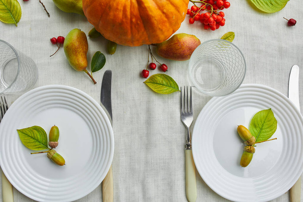 Jour de Thanksgiving ou Halloween table de dîner lieu décoratif avec citrouille, glands, feuilles de poires sur fond de nappe blanche, vue d'en haut, vue de dessus, plat laïc. - Photo, image