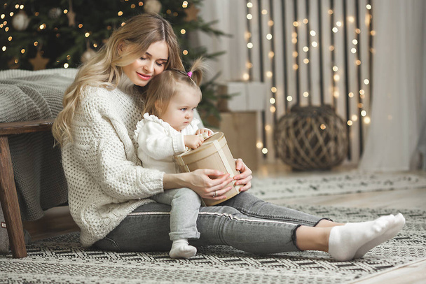 Houkutteleva nuori äiti, jolla on pieni vauva tytär joulun taustalla - Valokuva, kuva