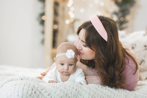 Attraktive junge Mutter mit ihrem kleinen Mädchen auf weihnachtlichem Hintergrund - Foto, Bild