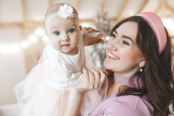 Attractive young mother with her little baby girl on christmas background - Photo, Image