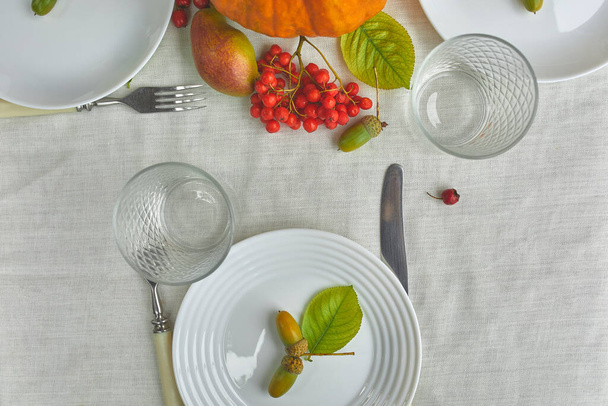 Jour de Thanksgiving ou Halloween table de dîner lieu décoratif avec citrouille, glands, feuilles de poires sur fond de nappe blanche, vue d'en haut, vue de dessus, plat laïc. - Photo, image
