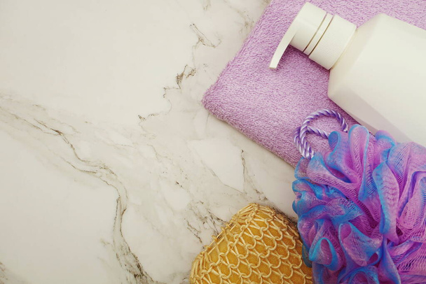 Shower accessories bath items shower bottle, sponge and fibre scrub on marble background - Fotó, kép