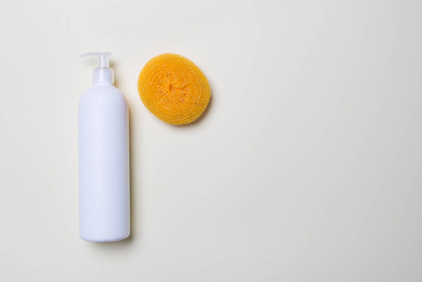white bottle with detergent and scrubber on white background  with copy space. - Foto, Imagem