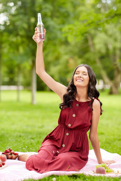 happy woman toasting drink at picnic in park - Photo, Image