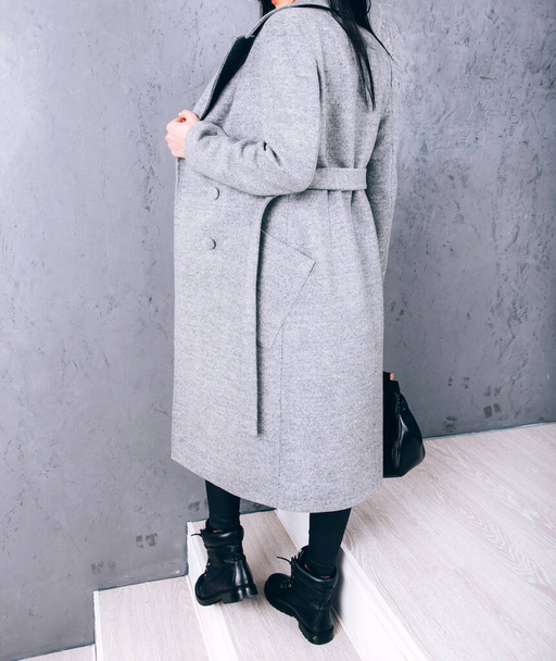 Studio photography of demi-season clothing. Young adult girl in an elegant coat on a gray background. Promotional women's coat. woman in a stylish autumn-spring coat. Casual wear. - Photo, Image