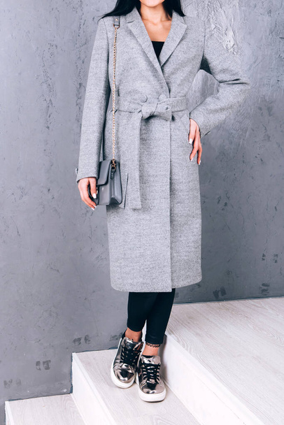 Studio photography of demi-season clothing. Young adult girl in an elegant coat on a gray background. Promotional women's coat. woman in a stylish autumn-spring coat. Casual wear. - Photo, Image