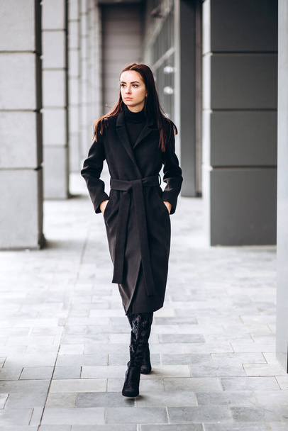 Portrait of a full-length girl on the street in autumn. Young adult girl in an elegant coat outdoors. Promotional coat. Young fashionable brunette woman in a stylish woolen autumn and spring coat. - Foto, immagini