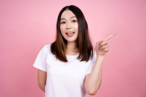 Asian woman pointing to the copy space, Pink background studio. - Foto, immagini