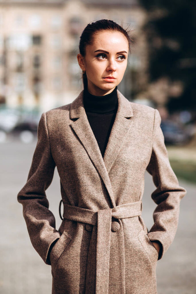 Detail of a female coat close-up. Young adult girl in an elegant coat outdoors. Promotional women's coat. Young fashionable brunette woman in a stylish woolen autumn and spring coat. - Zdjęcie, obraz