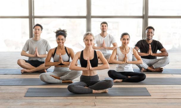 Clase Internacional de Yoga. Grupo de personas deportistas del milenio sentados en posición de loto - Foto, Imagen