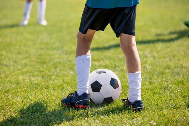 Football players feet close up. Sports training  on a grass field background. Boy in a sportswear. Player wearing white football socks and soccer cleats. Football horizontal background. Sport training - Photo, Image