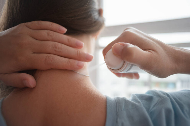 Woman is spraying her neck with the pain reliever spray close up. - Fotó, kép
