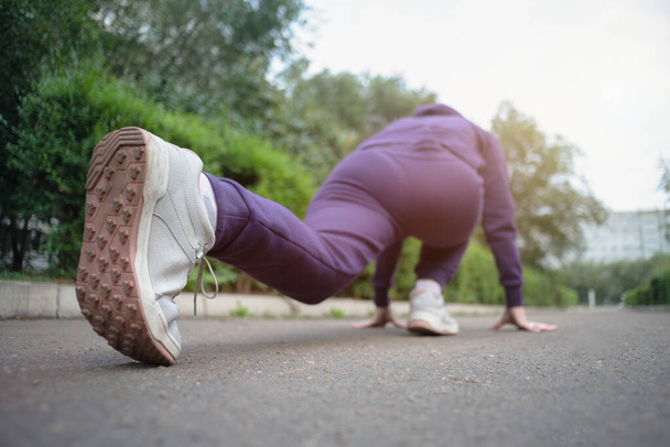 Woman a runner is stretching on the asphalt road outdoors. - 写真・画像